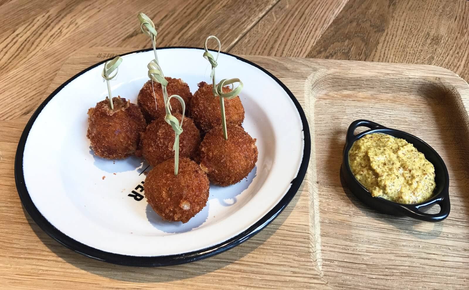 6 Niederländische Bitterballen mit Senf auf einem Teller