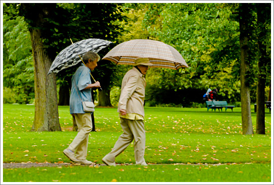 Zwei ältere Damen mit Regenschirm im Park