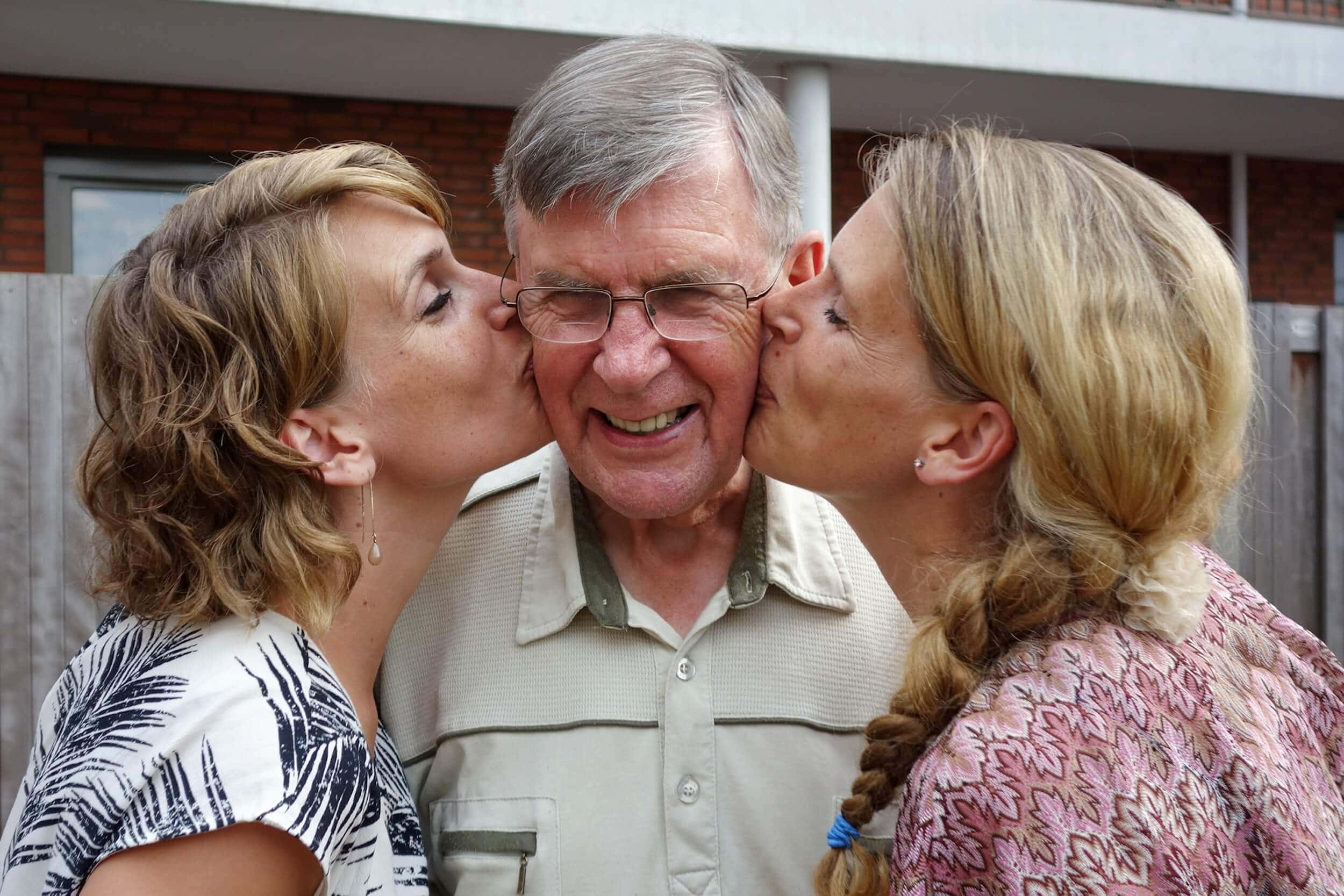 Zwei Töchter küssen ihren Vater
